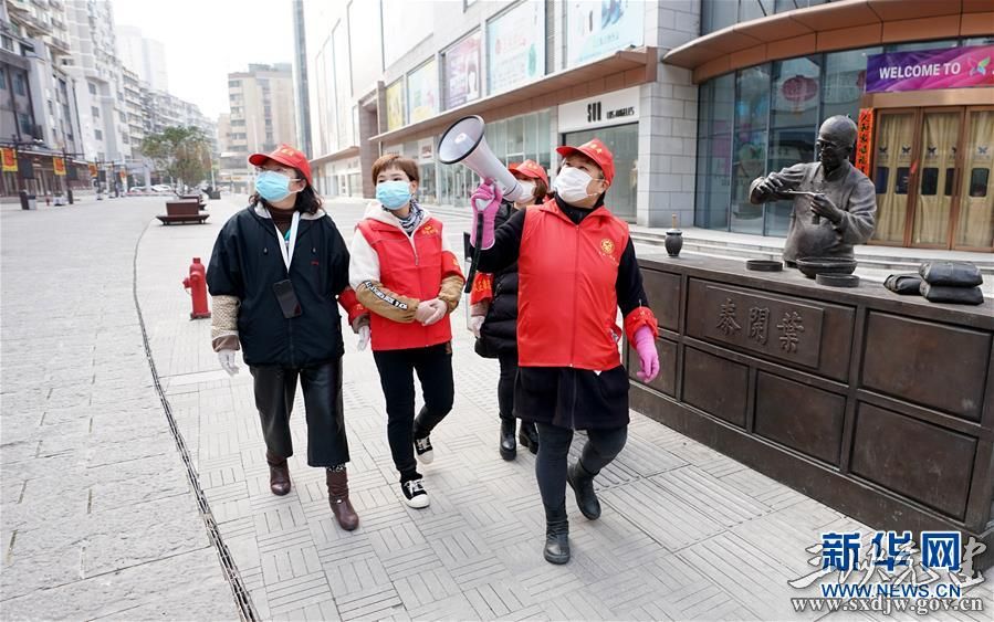 武汉市汉正街石码社区党委书记兼居委会主任韩小琴(右一)带领社区工作人员向步行街旁的居民宣传防疫知识(2月13日摄)。 新华社记者 王毓国 摄